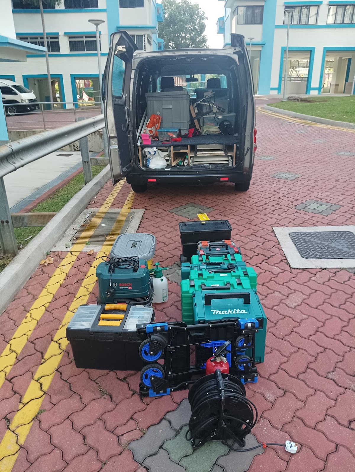 Gunther's work van with rear doors open, packed with tool shelving, Bosch and Makita cases laid out