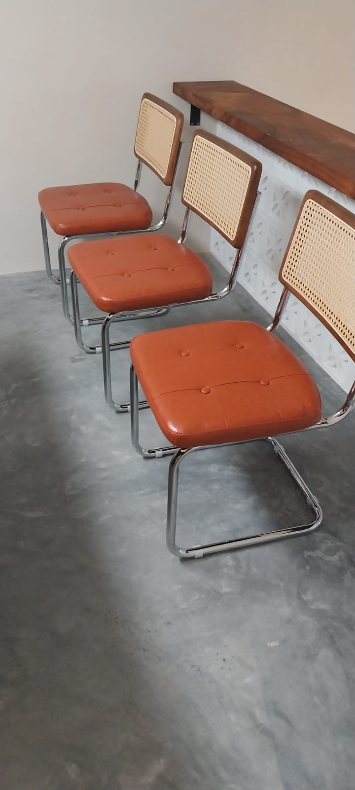 Three cane back cantilever chairs assembled at a wooden bar counter