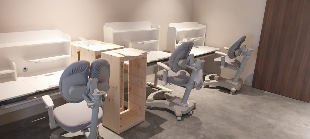 A row of study desks and ergonomic chairs mid assembly